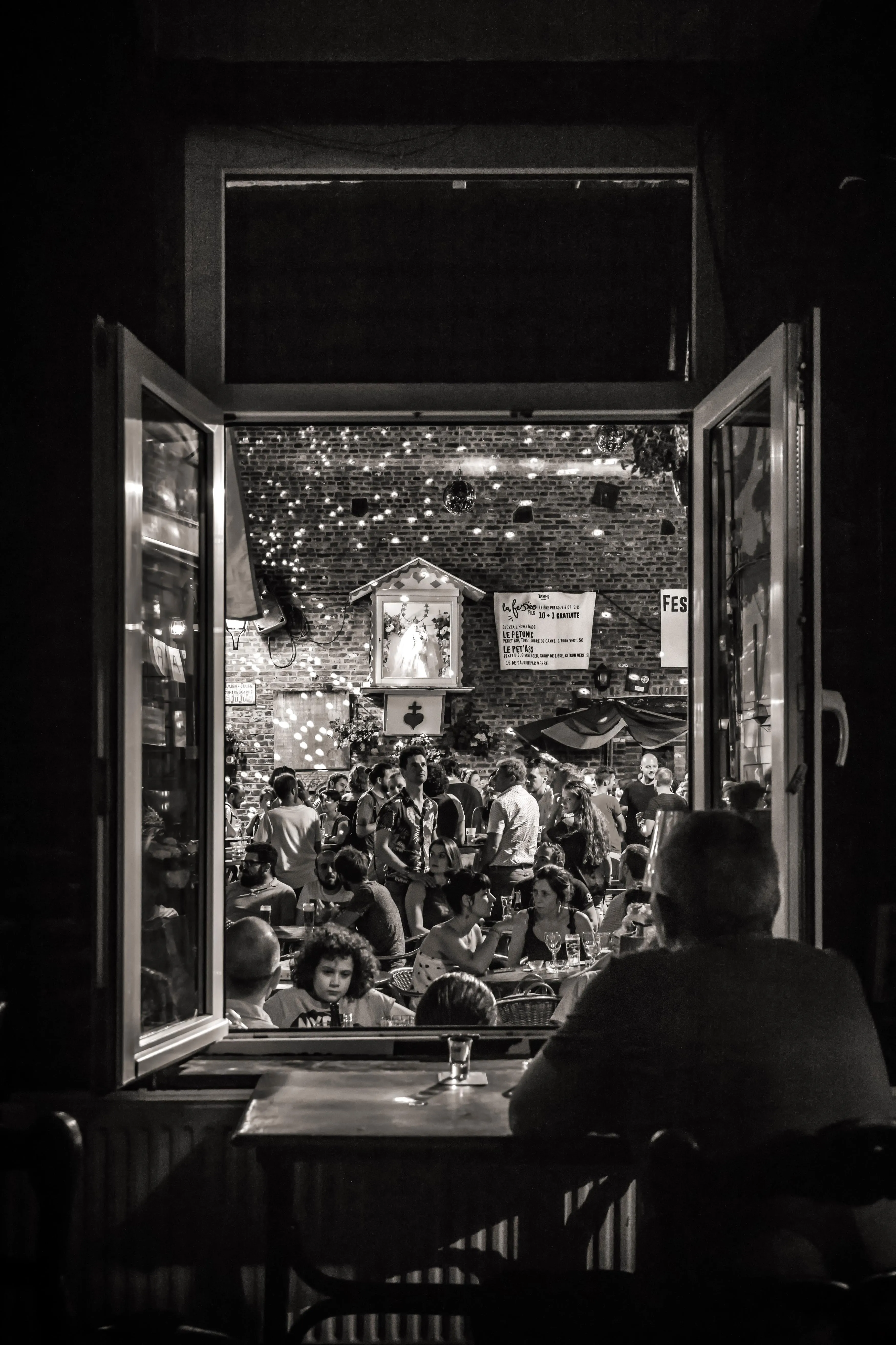 Crowded terrace seen through a window, Liège in celebration