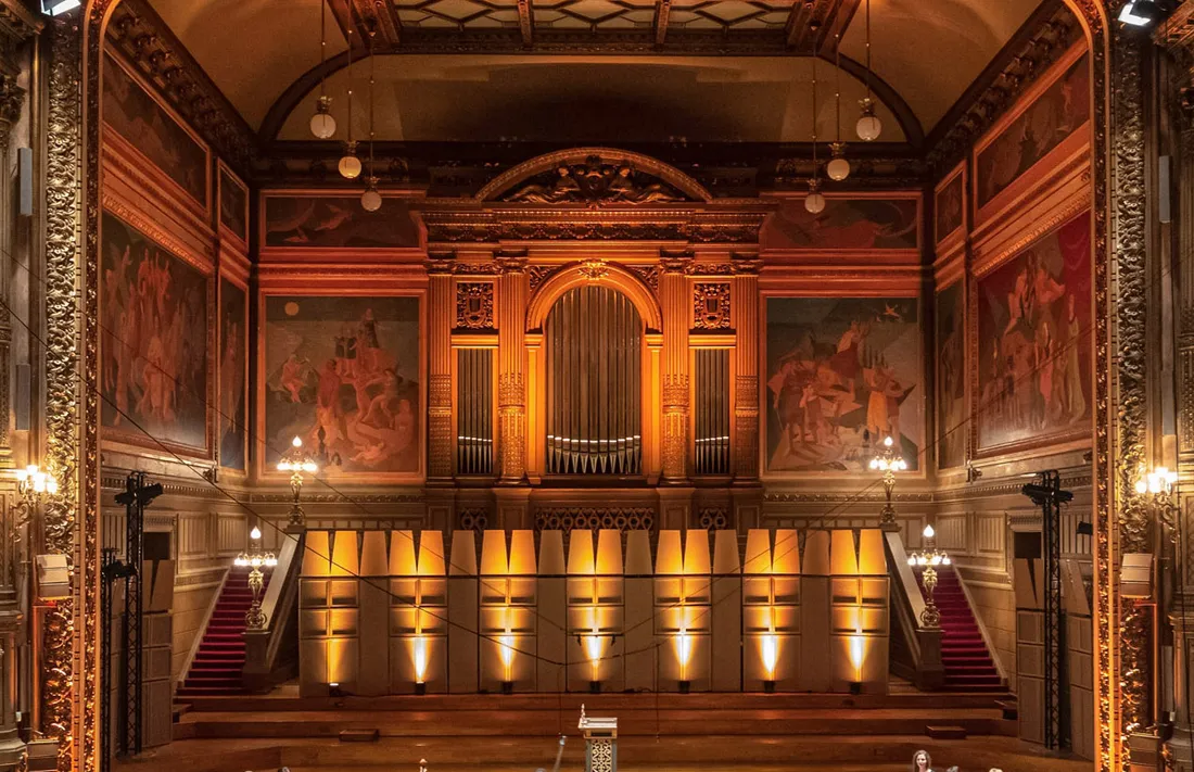 Edgar Scauflaire’s mural paintings on the stage walls of the Liège Philharmonic Hall, under concert lighting